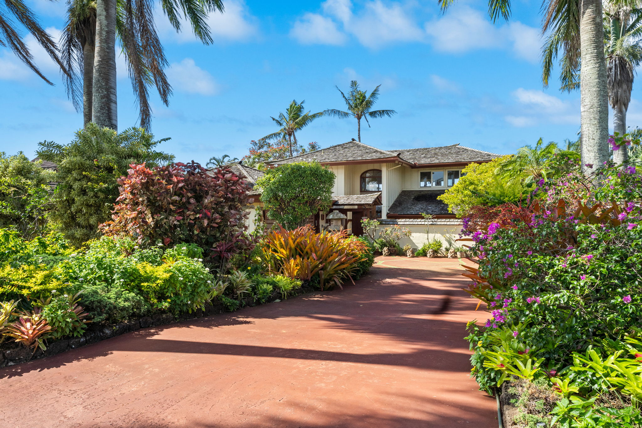 Grand tropical driveway approach lined with lush landscaping